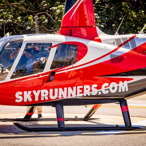 Red helicopter with 'SKYRUNNERS.COM' parked on a helipad.