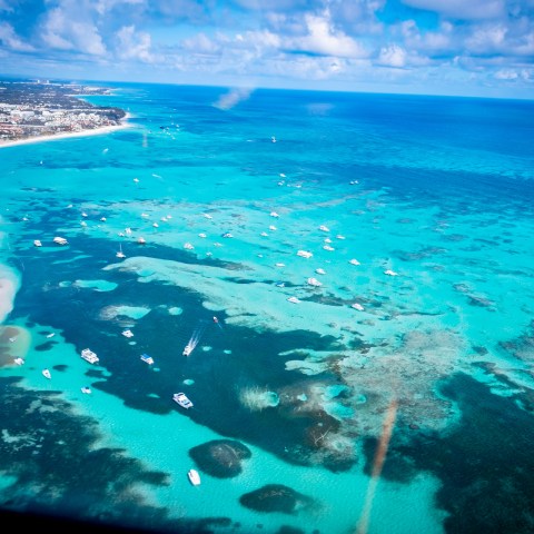 Aerial view of a tropical coastline with turquoise water and scattered boats.