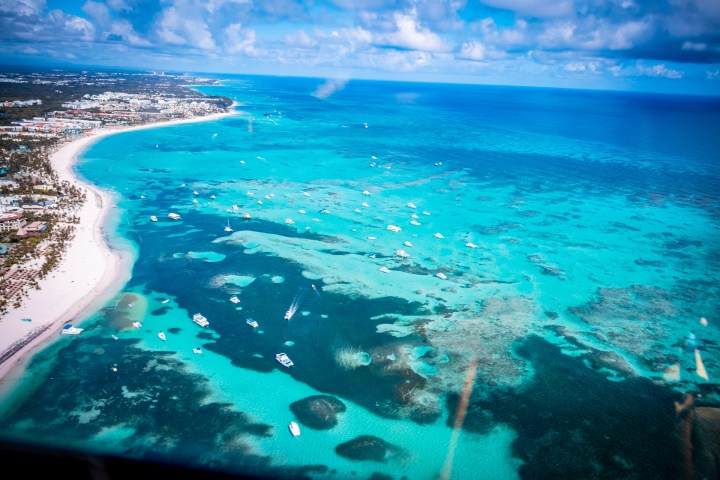 Aerial view of a tropical coastline with turquoise water and scattered boats.