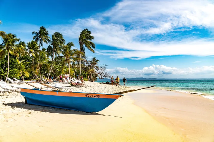 a boat sitting on top of a sandy beach next to the ocean
