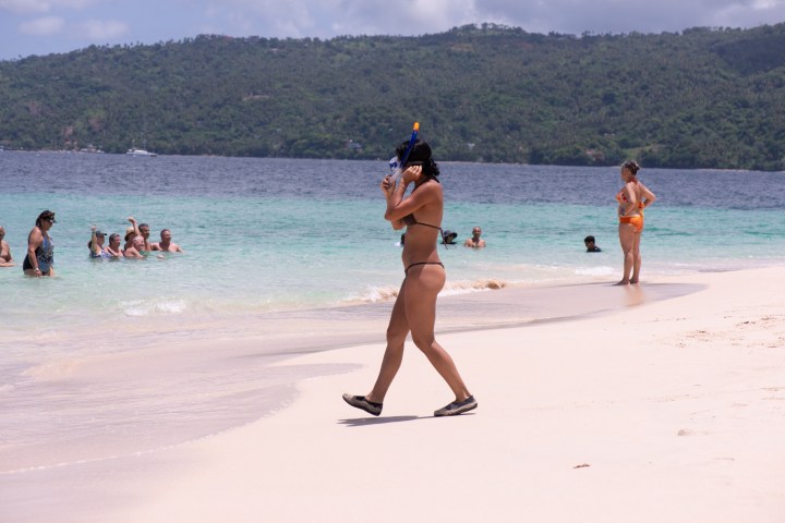 a group of people on a beach with a mountain in the background