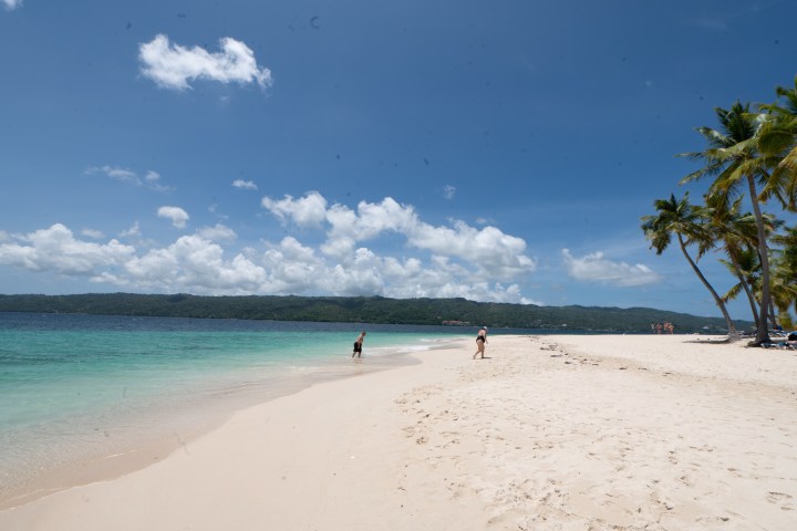 a group of people standing on top of a sandy beach