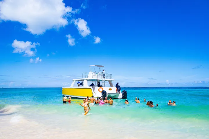 People swimming near a yellow boat in clear blue ocean under a sunny sky.
