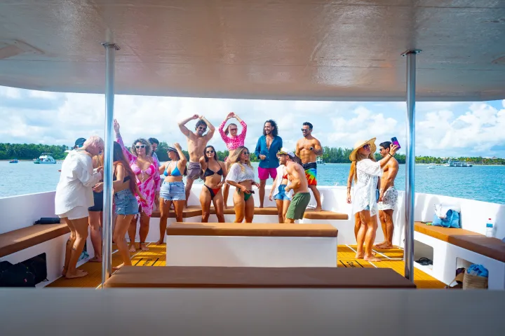 Group of people in swimwear partying on a boat under a cloudy sky.