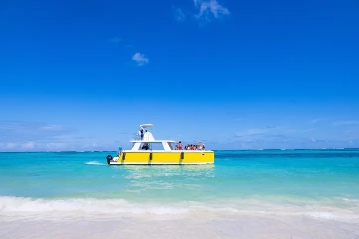 Yellow boat with people on turquoise sea under clear blue sky